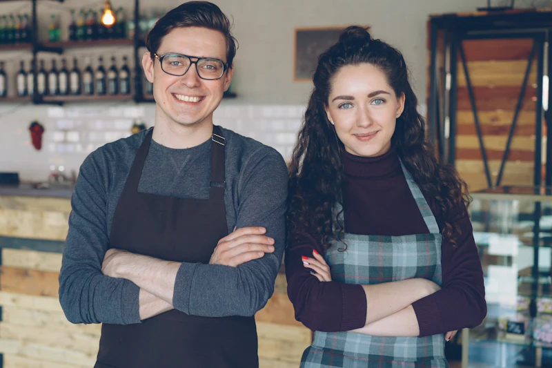 Two café owners standing proudly behind their counter