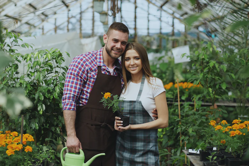 Couple tending plants in their garden centre greenhouse