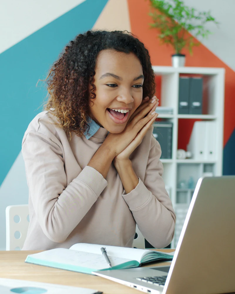 Excited New Zealand business owner checking her business finance options on a laptop
